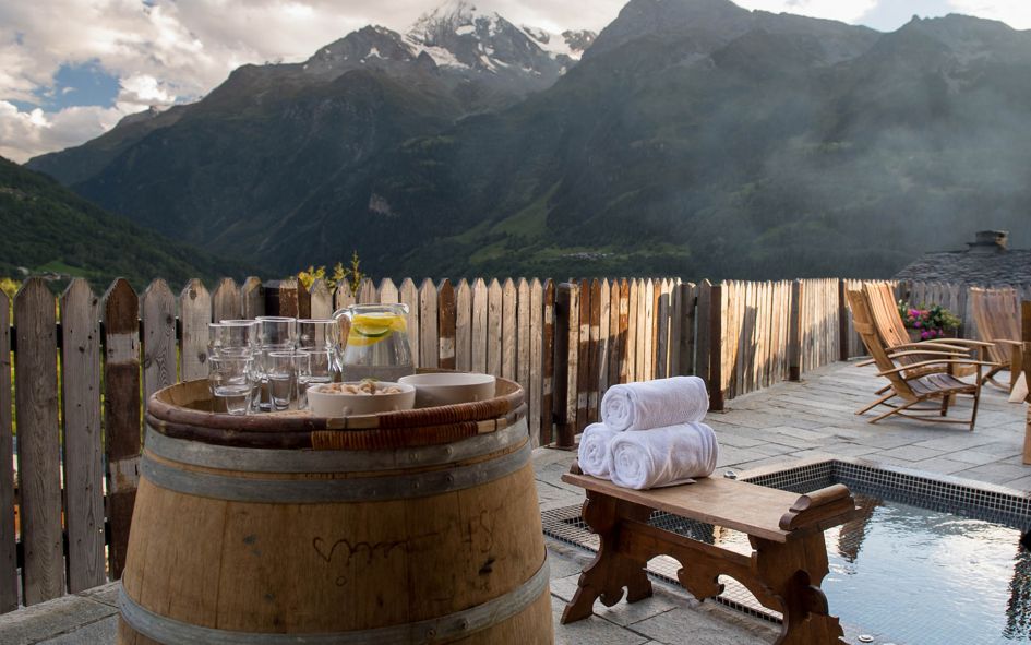 Chalet Pelerin, in Sainte Foy, is a true alpine mountain retreat. This summer chalet's outdoor hot tub offers privacy from a fence around the perimeter of the terrace. In the foreground, a barrel holds refreshments for your relaxation. In the background, monumental mountain views feature.