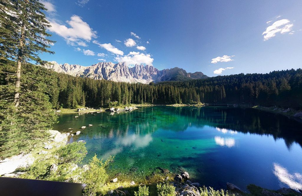 Lago di Carezza photo showing the green and blue waters with the fir forest and mountains in background.
