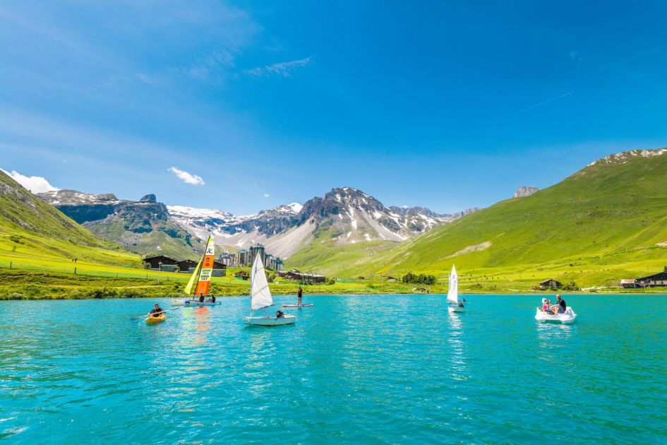 Lac de Tignes showcases beautiful tranquil waters, perfect for enjoying a range of watersports (including paddleboarding, canoeing and sailing) in front of a mountain backdrop.