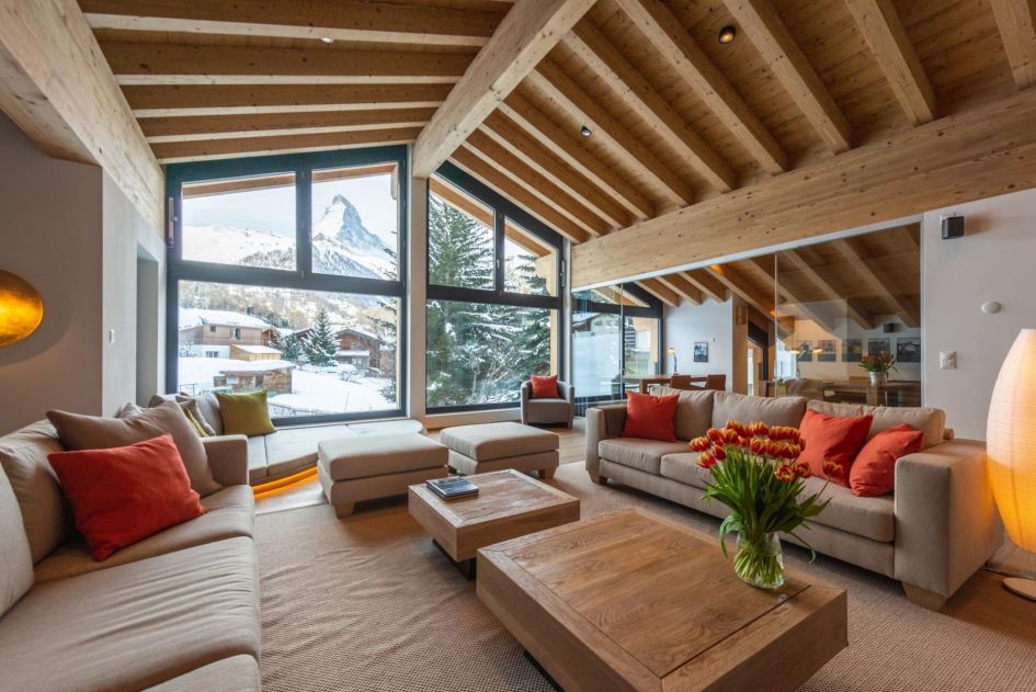 Chalet Tuftra Findelbach's open living room is decorated in light colour tones, which perfectly complements high wooden ceilings and light brown furniture. All eyes are drawn to the large picture window at the back of this room, however, which frames a clear view of the iconic Matterhorn mountain.