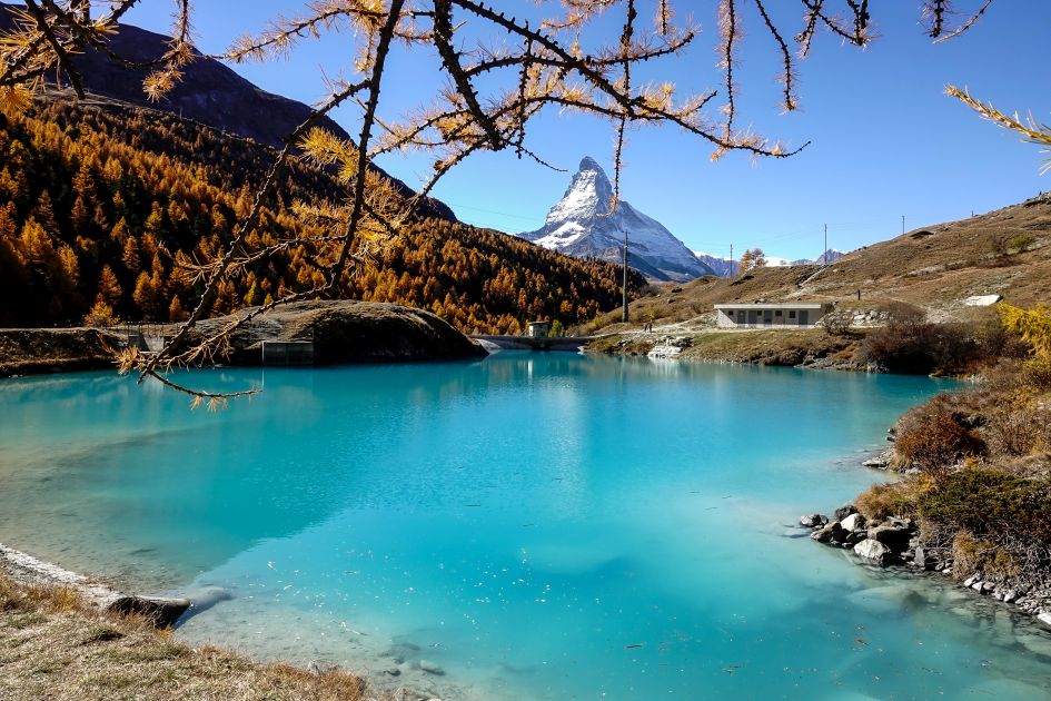 Zermatt's Moosijisee Lake in autumn is a sight to behold with a beautiful body of turquoise water surrounded by golden hills and trees, and the Matterhorn standing tall in the background.