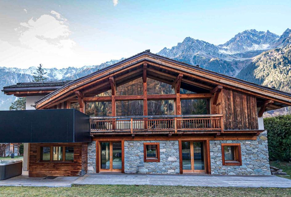 Chalet Bonami, Chamonix. Stone and wood exteriors of the luxury Chalet Bonami in summer with the mountains of Chamonix in the background.