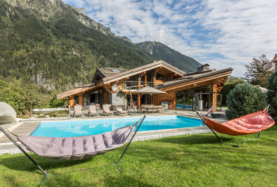Chalet Couttet, Chamonix. Outdoor pool in Chalet Couttet's garden, Chamonix. Padded hammocks in the foreground for ultimate relaxation and summer mountain views.