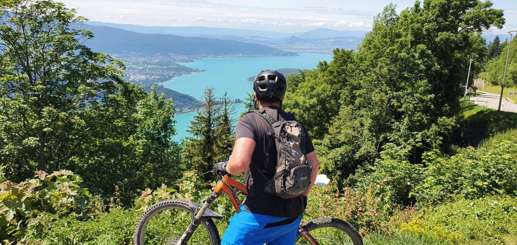 Cycling trip in Morzine A man with a bike overlooks one of the lakes in Morzine while enjoying his eco-conscious summer mountain holidays.