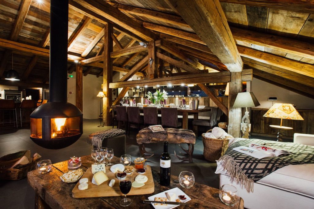 Chalet Debussy, Morzine Interior of Chalet Debussy, an eco-conscious summer mountain chalet in Morzine. Showcasing the floating fireplace, bar area, and a cheeseboard with wine.