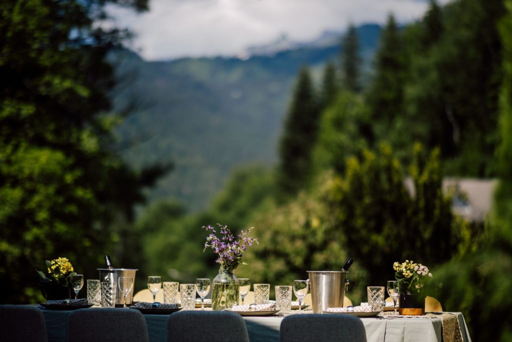Alfresco dining in Morzine. Outdoor dining table adorned with flowers and glasses, in the sunshine. A great place to spend time together on a sustainable mountain holiday