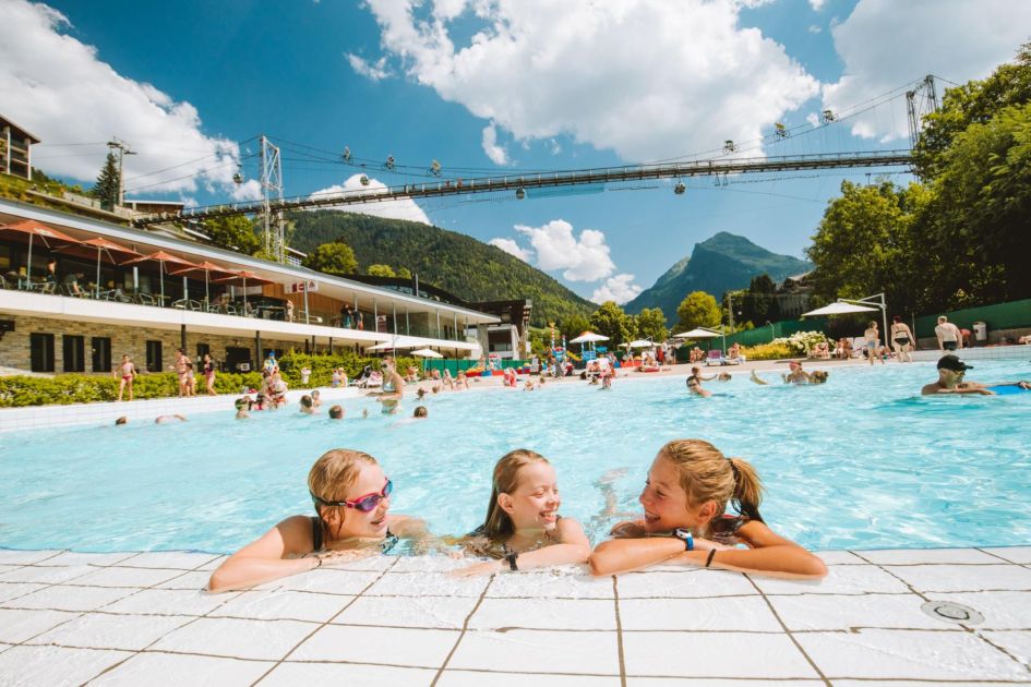 Children swimming in the outdoor pool at the Parc des Dérêches beneath the suspension bridge.