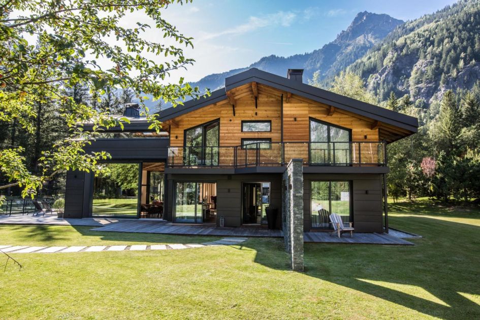 Exterior view of Chalet Dalmore showcasing its large open garden and incredible mountains behind the property.