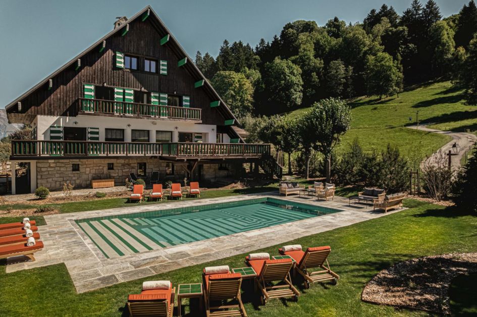 A beautiful outdoor swimming pool with sun loungers, surrounded by summer greenery.