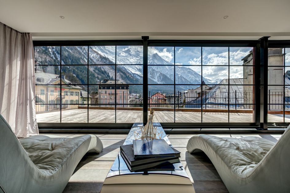 A cosy seating arrangement in the modern living area, which opens out onto the roof terrace in front of the stunning mountain scenery.
