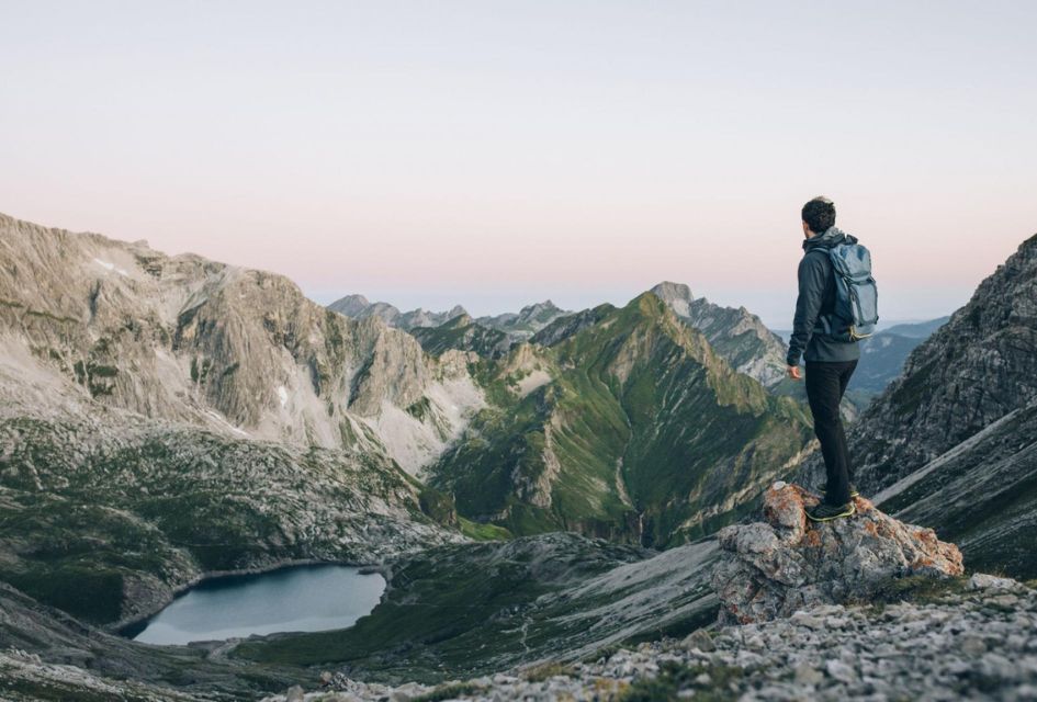 An explorer hiking and looking out across the impressive jagged mountain peaks.