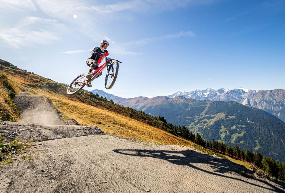 Credit: Verbier Tourism Downhill mountain biking trail with jumps and impressive mountain views in the distance.